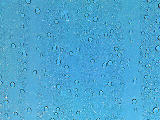 Rain water drops on glass against blue sky abstract texture
