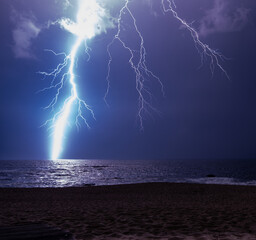Powerful lightning bolt striking ocean during a storm, lighting up the sky.