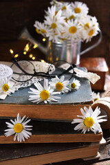 Fototapeta na wymiar rustic style still life with old books and daisy flowers on wooden table