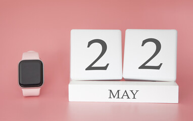 Modern Watch with cube calendar and date 22 may on pink background. Concept spring time vacation.