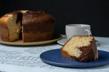 HOMEMADE RUSTIC CAKE, ON THE TABLE HAVING A CUP OF COFFEE IN THE BACKGROUND