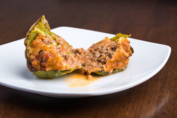 Stuffed green bell pepper served on a plate and cut in half.