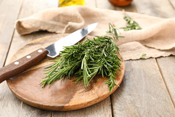 Plate with fresh rosemary and knife on table