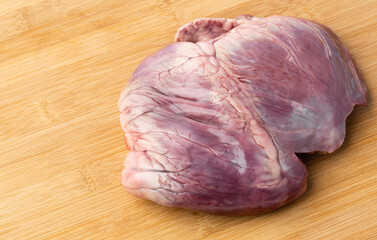 Fresh pig heart from market on wooden cutting board in kitchen for make a food