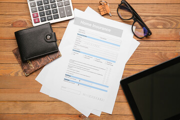 Home insurance form with wallet, key, calculator and tablet computer on wooden background
