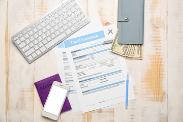 Obraz premium Travel insurance forms with money, mobile phone, passport and computer keyboard on table