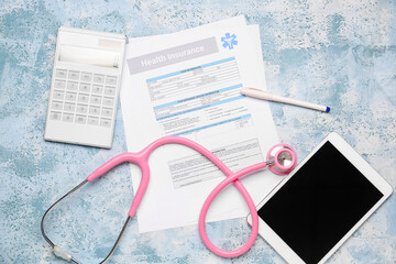 Health insurance form with stethoscope, tablet computer and calculator on color background