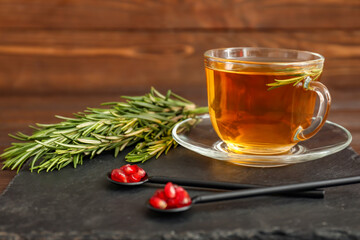 Cup of hot tea with rosemary on table