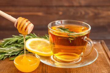 Cup of hot tea with rosemary and honey on table