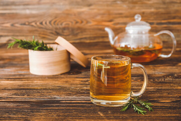 Cup of hot tea with rosemary on table