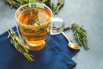 Cup of hot tea with rosemary on dark background
