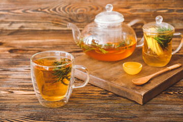 Cup of hot tea with rosemary on table
