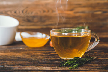 Cup of hot tea with rosemary on table