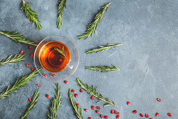 Cup of hot tea with rosemary on dark background