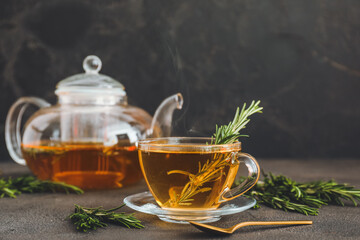 Cup of hot tea with rosemary on dark background