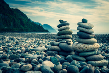 Masonry stones in the form of a figure. Pebble construction on the seashore. View on a blue background. Cloudy. Evening. The coast of the Black Sea, Georgia.