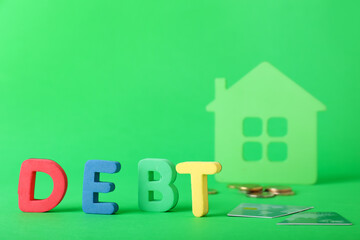 Figure of house, coins and word DEBT on color background