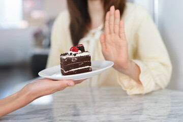 Say no to sweet during diet. Woman refusing to eat cake and push off.