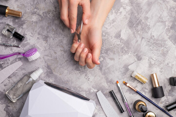 The girl does nails on a concrete gray background, with tools for nail care. Top view. Beauty and hygiene to please the nails.