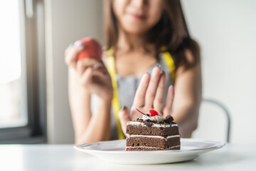 Choose right food for you health. Person eat dessert holding green apple and cake to compare calories as sweet menu to eat during diet.