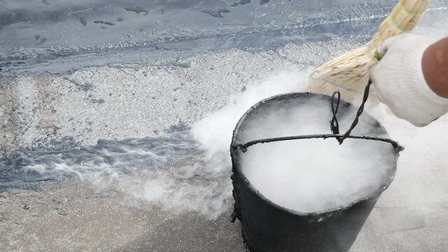 Working seals cracks on the roof with the help of melted tar. Roof repair