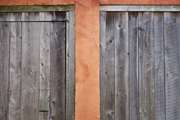Pale peach colored mason wall with two old and weathered wooden doors