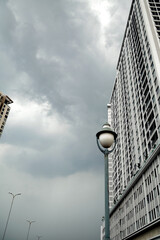 Obraz premium Tall gray buildings and lanterns in a city business district. Dull depressing city view on a cloudy day. Architectural background with copy space