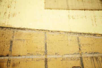 Brick wall of an old house painted yellow and ocher colors. Weathered stained wall textured background
