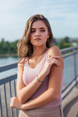 Pretty young woman posing on the old rusty transport bridge over the river during sunset.