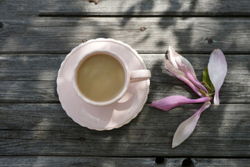 Fototapeta na wymiar Pink magnolia flower and a mug with a drink