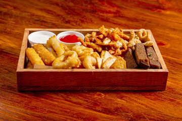 Potato chips, squid, shrimp, cheese sticks, with red sauce, ketchup, beer snack on the table