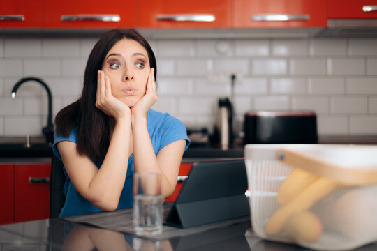 Bored  Woman with Pc Tablet Sitting in the Kitchen