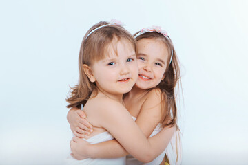 two little happy girls smiling on white background. Portrait of children hugging. The concept of relationships in the family, friends, sisters, couple in love. Copy space