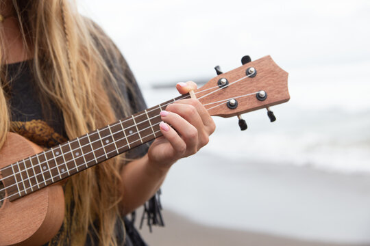 A young beautiful woman walks with a ukulele on the beach. Walk with a ukulele on the beach.
