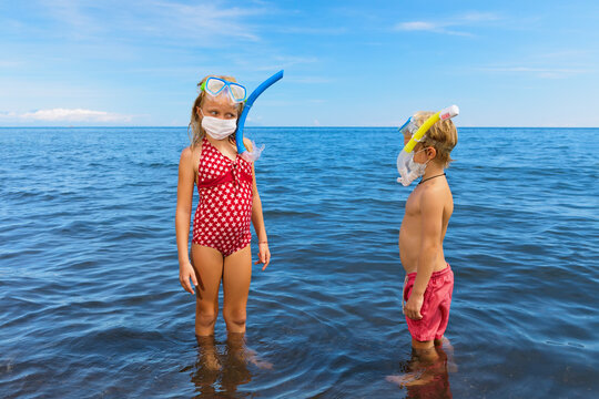 Kids in snorkeling mask wear surgical face mask on sea beach. Cancelled cruises, tours due coronavirus COVID 19 world epidemic. Travel ban for family vacation, tourism industry crisis at summer 2020