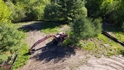 Aerial View of a Old Excavator at a Construction Site in a Remote Forest Area during Clear Summer Weather