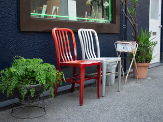 White and red empty chairs near a cafe on the street. The cafe has no visitors, so the waiting chairs are empty.