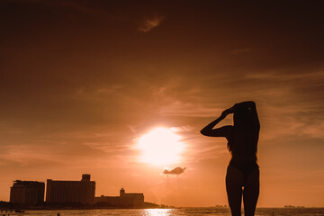 Slender blonde woman admires the sunrise at a Carribean sea.