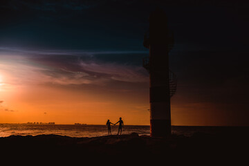 Fototapeta premium The silhouette of a couple and a huge lighthouse.