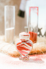 Bride and groom pouring colorful different colored sands into the crystal vase close up during symbolic nautical decor destination wedding marriage ceremony on sandy beach in front of the ocean 