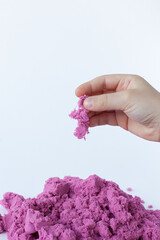 Purple kinetic sand in hand isolated on a white background.