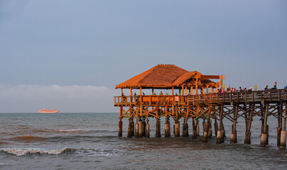 Cocoa Beach Pier at sunset. Unrecognizable people walk near the ocean. Paradise Beach and Atlantic Ocean Sunset.