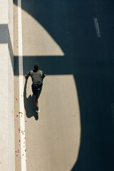 Fit young male athlete in starting position standing on road, view from the top