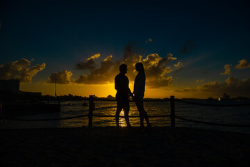 Silhouettes of men and women against the backdrop of the setting sun.