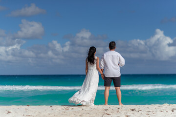A man and a woman walk on the seashore and look at the horizon.