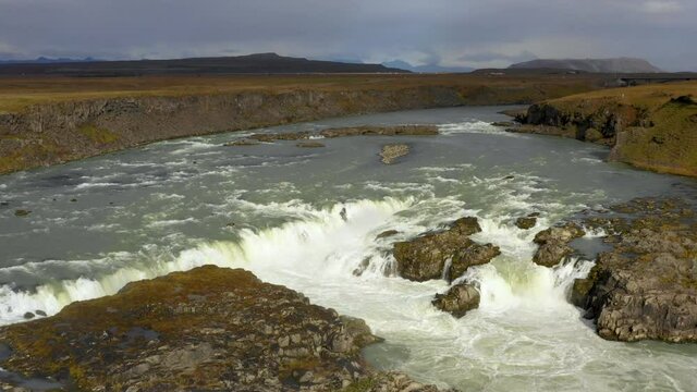 Stunning Low Aerial Drone Shot Of Iceland Landscape, Moving Slowly Forwards Over Rocks And Waterfalls, With Flat Lands And Moutains In The Distance.