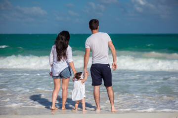 Parents with a small child walk on the beach and admire the horizon.