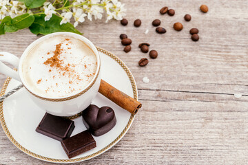 Сup of coffee and homemade chocolate sweets on a wooden background.Coffee beans, white flowers and cinnamon sticks adorn the composition.Сoncept of healthy food and healthy desserts.Copy space
