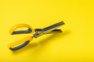 Scissors with five blades on a yellow background.