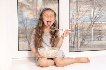 A little cute girl preparing the dough in the kitchen at home, happy family concept